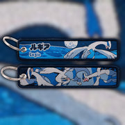 Lugia silver and blue woven fabric keytag attached to metal keyring featuring embroidered Lugia artwork