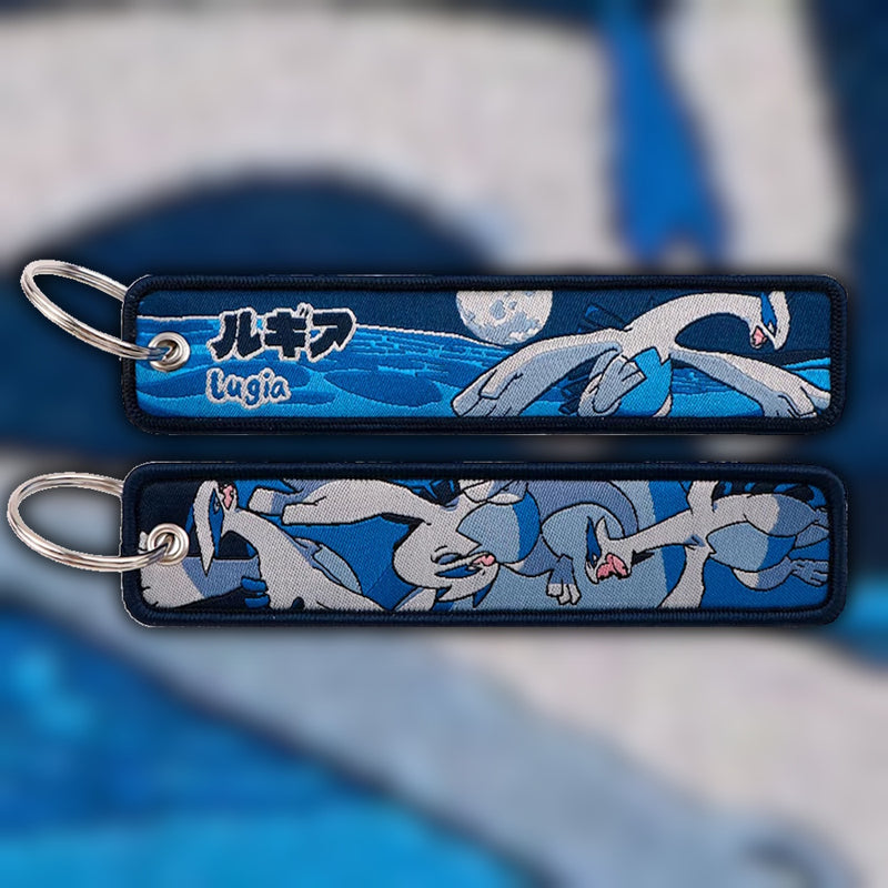 Lugia silver and blue woven fabric keytag attached to metal keyring featuring embroidered Lugia artwork