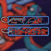 Deoxys crimson and teal woven fabric keytag attached to metal keyring featuring embroidered Deoxys artwork